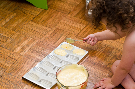 Child filling madeleine cookie molds with batter