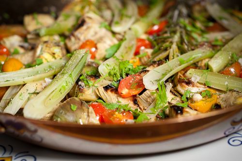 Saute pan full of braised artichokes, fennel and cherry tomatoes